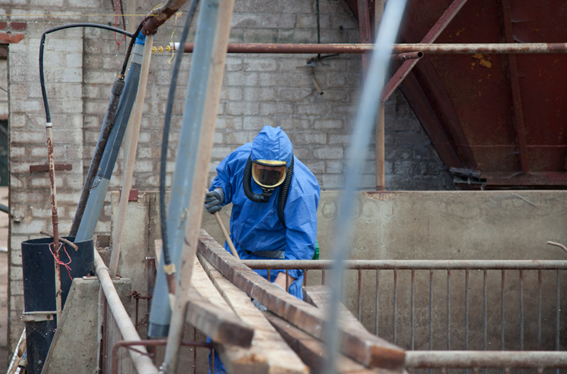 Técnico realizando un proceso de retirada de amianto de un tejado de un edificio público."